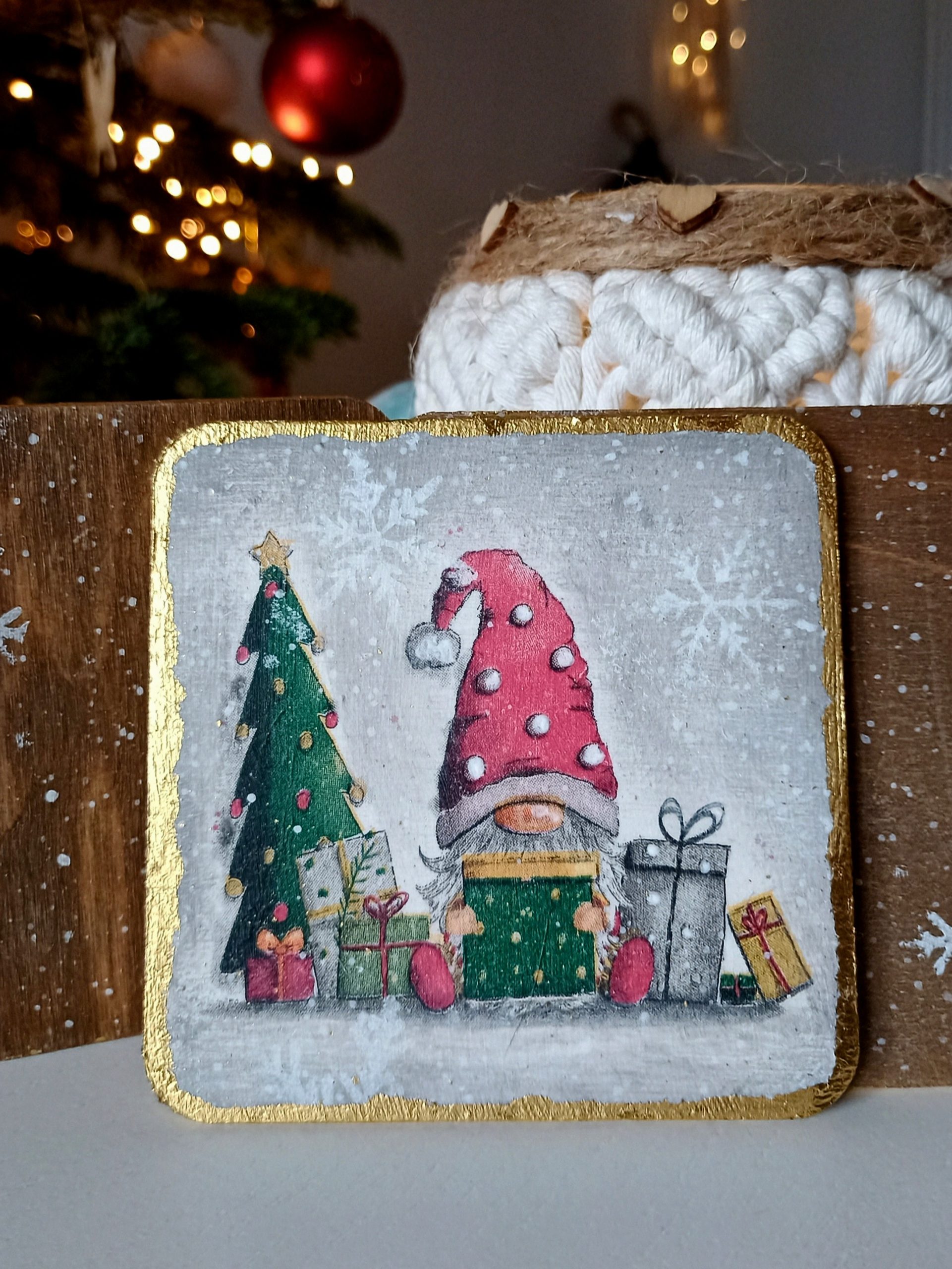 Świąteczna podkładka pod kubek ze skrzatem – ręcznie zdobiona techniką decoupage, malowana i wykończona złoconymi brzegami. Piękna dekoracja świąteczna i praktyczne rękodzieło. Zabezpieczona lakierem odpornym na wysokie temperatury – idealna na prezent lub do codziennego użytku.